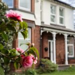 The front of this award winning Bed and Breakfast in Cheshire, from behind a flowering bush