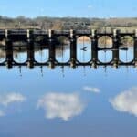 Walk along the River Weaver. Image shows a view of the River Weaver and the weir near Dutton Locks. Beautifull with the sky mirrored in the River water.